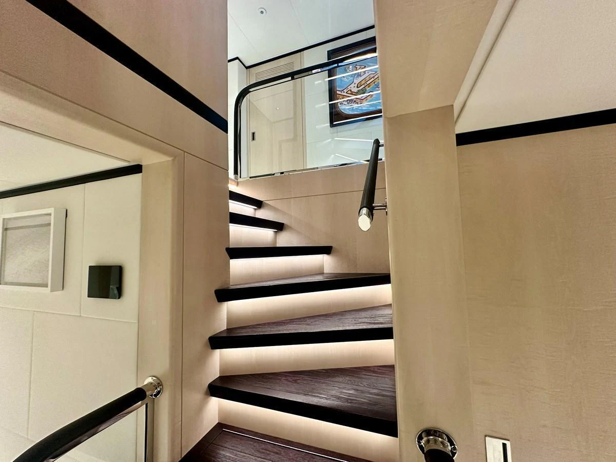 A modern, well-lit staircase with sleek design elements connects different levels of the yacht's interior. aboard OPTIMISM Yacht for Sale