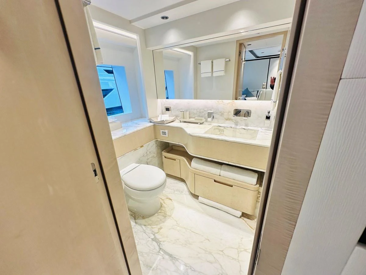 The yacht's bathroom features a sleek design with modern fixtures and ample lighting. aboard OPTIMISM Yacht for Sale