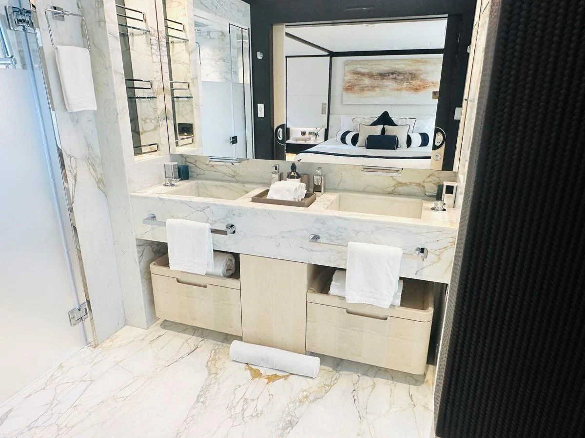 The yacht's bathroom features a luxurious double vanity with elegant marble finishes. aboard OPTIMISM Yacht for Sale