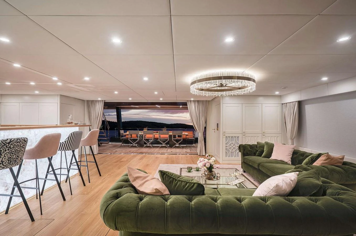 The salon features luxurious green velvet seating and a chic bar area, opening to an expansive view. aboard 100 SUNREEF POWER NEXT Yacht for Sale