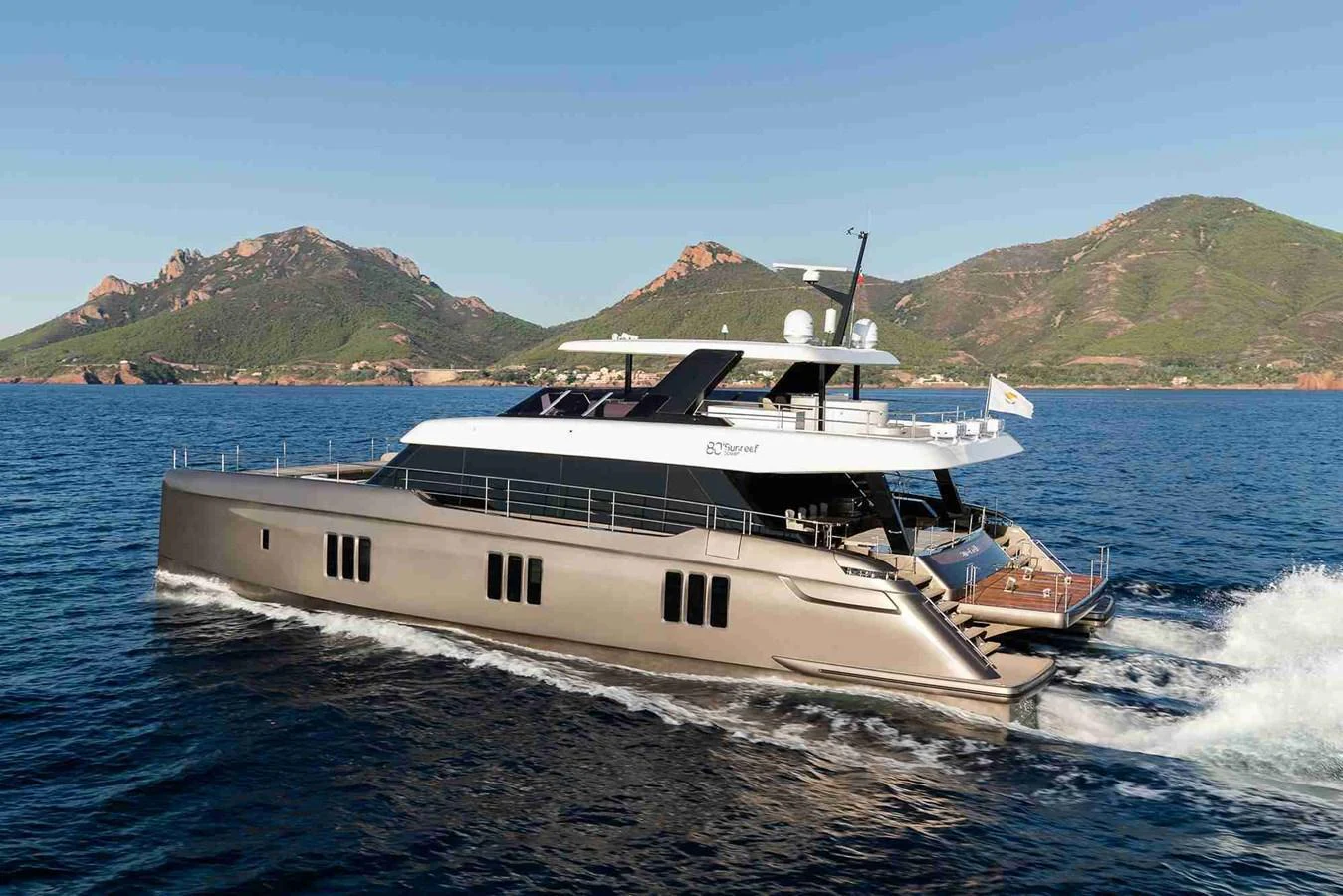 A sleek and modern yacht cruising on the open water with scenic mountains in the background. aboard 80 SUNREEF POWER NEXT Yacht for Sale