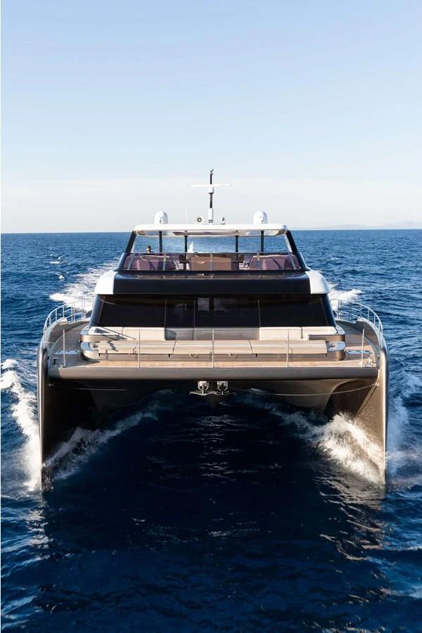 A sleek yacht cruises forward on the open sea under clear skies. aboard 80 SUNREEF POWER NEXT Yacht for Sale
