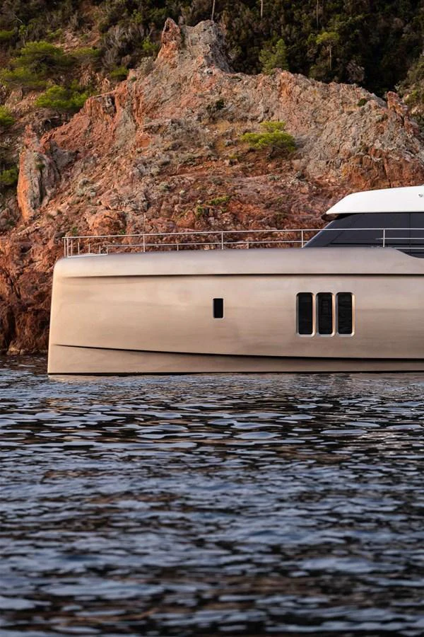 The yacht is seen against a rocky coastal backdrop, showcasing its sleek and modern design. aboard 80 SUNREEF POWER NEXT Yacht for Sale