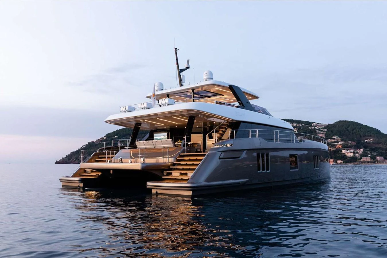 A sleek, modern yacht is anchored in calm waters, showcasing its spacious aft deck and elegant design. aboard 80 SUNREEF POWER NEXT Yacht for Sale