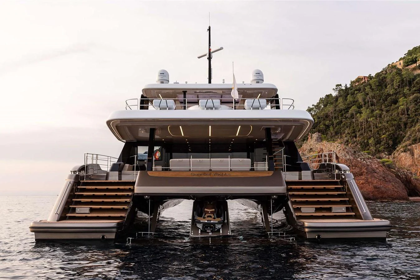 A luxurious yacht with multiple decks and a tender garage, set against a scenic coastal backdrop. aboard 80 SUNREEF POWER NEXT Yacht for Sale