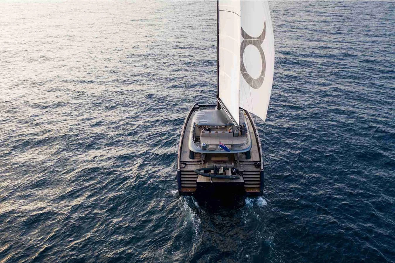A sleek sailing yacht glides gracefully over calm waters at sunset. aboard SUNREEF 80 NEXT Yacht for Sale