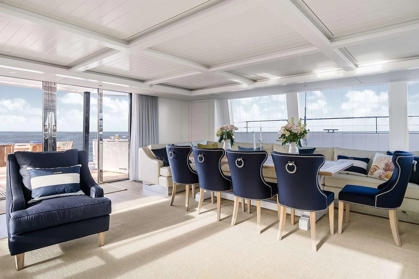 The salon features elegant seating with a view of the ocean through large windows. aboard SUNREEF 80 NEXT Yacht for Sale