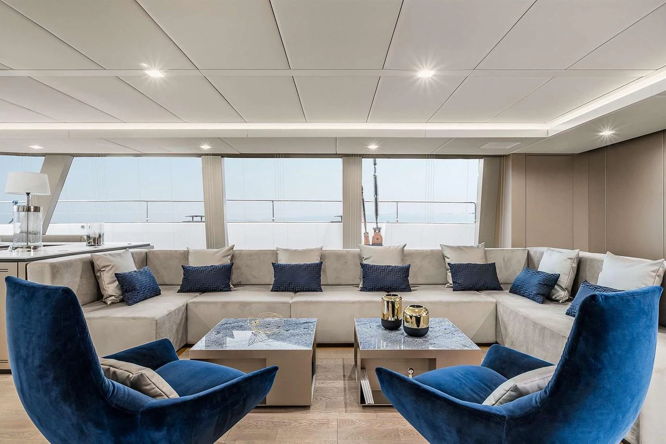 The salon features a spacious seating area with plush blue and beige furnishings, creating a luxurious and inviting atmosphere. aboard SUNREEF 80 NEXT Yacht for Sale