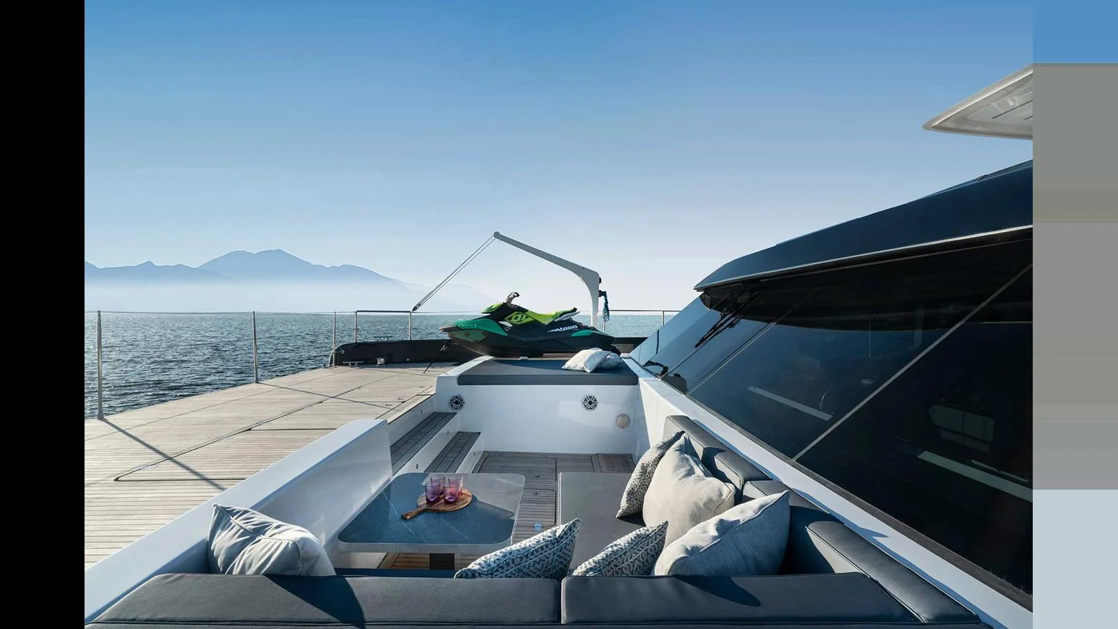 The aft deck features a comfortable seating area with a view of the water and mountains in the distance. aboard 70 SUNREEF POWER NEXT Yacht for Sale