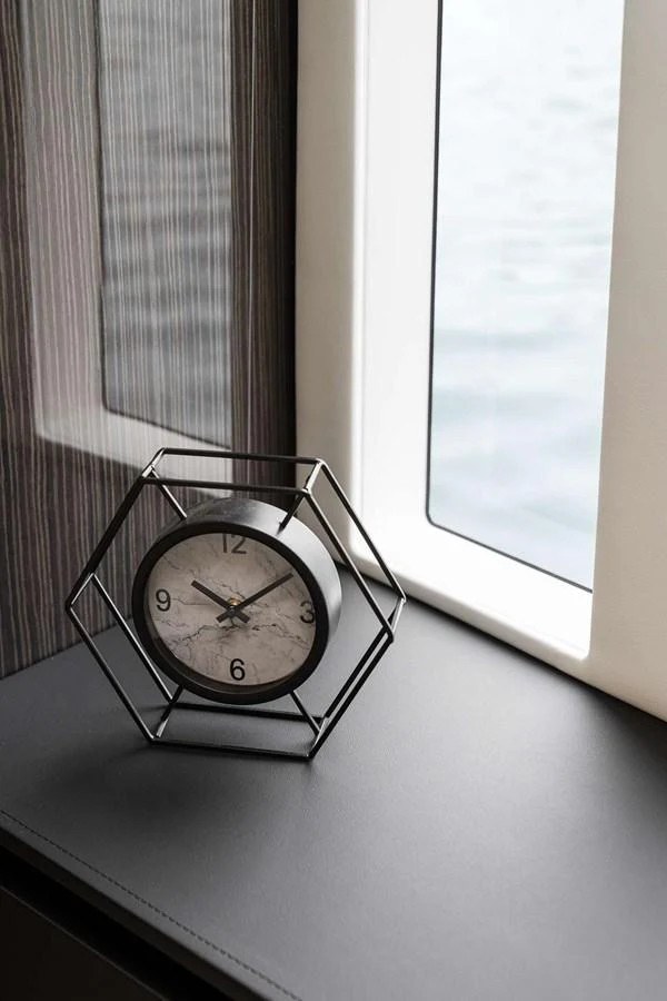 A stylish clock sits on a sleek surface next to a window with a view of the water. aboard SUNREEF 70 NEXT Yacht for Sale