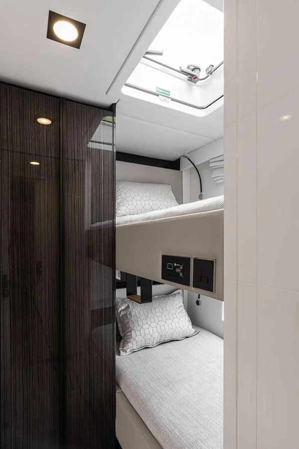 A cozy bunk room with modern finishes and natural light from a skylight. aboard SUNREEF 70 NEXT Yacht for Sale