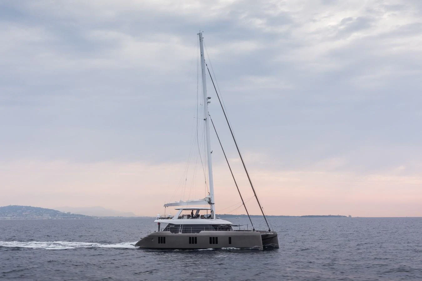 A sleek catamaran glides smoothly over calm waters under a serene sky. aboard SUNREEF 70 NEXT Yacht for Sale