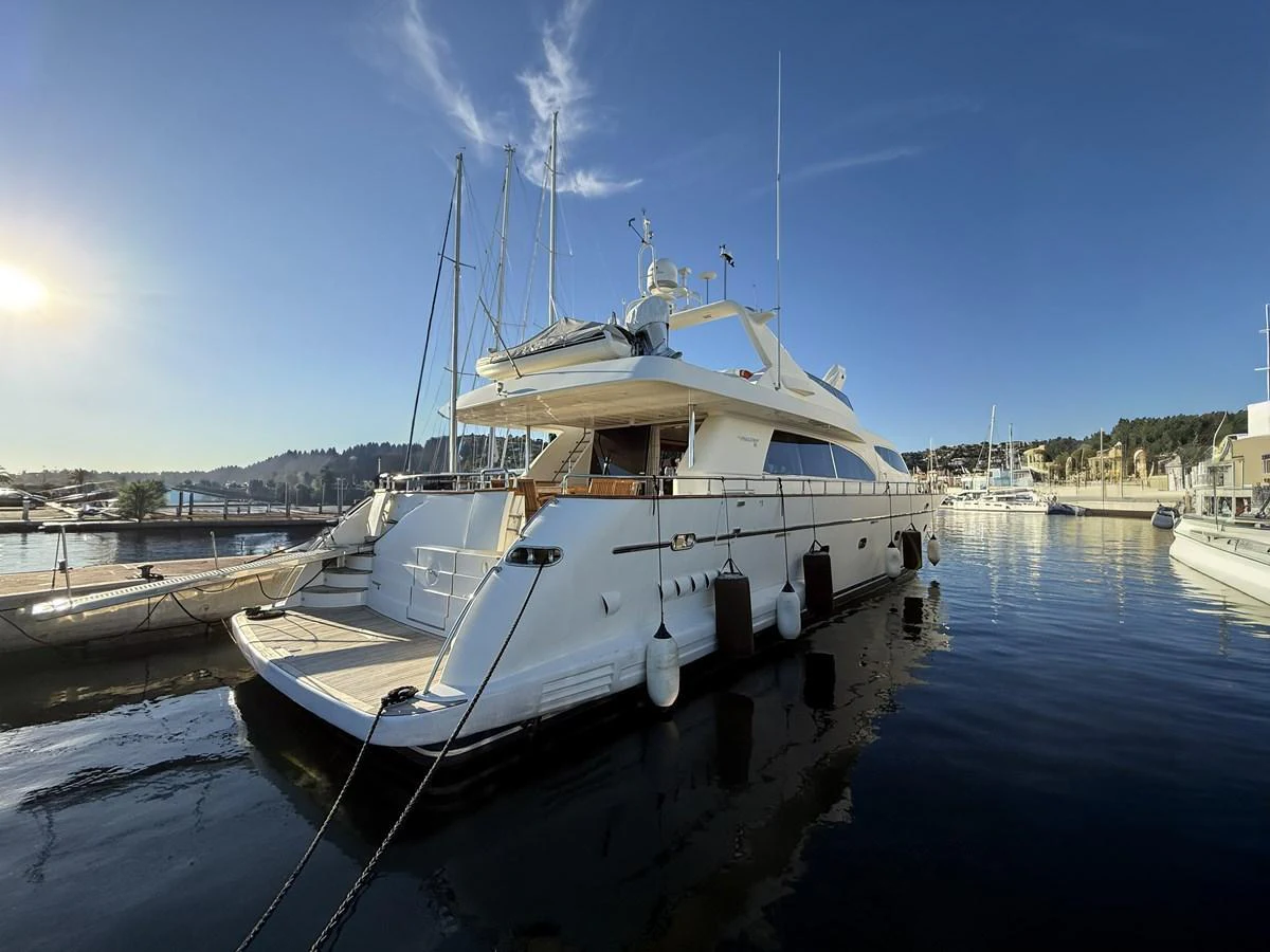 A sleek yacht is docked at a marina under a clear blue sky. aboard SIKOY Yacht for Sale