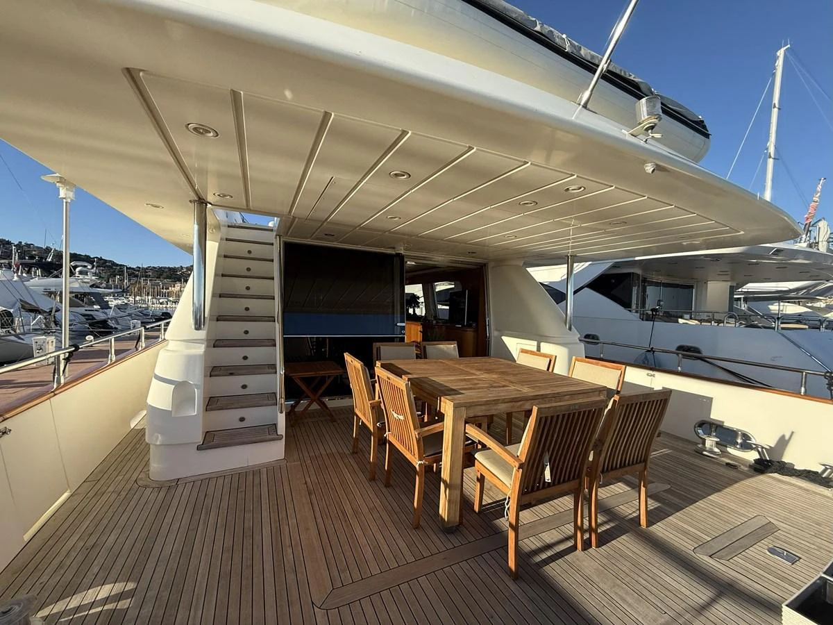 The aft deck features a spacious outdoor dining area with wooden furniture, perfect for alfresco meals. aboard SIKOY Yacht for Sale