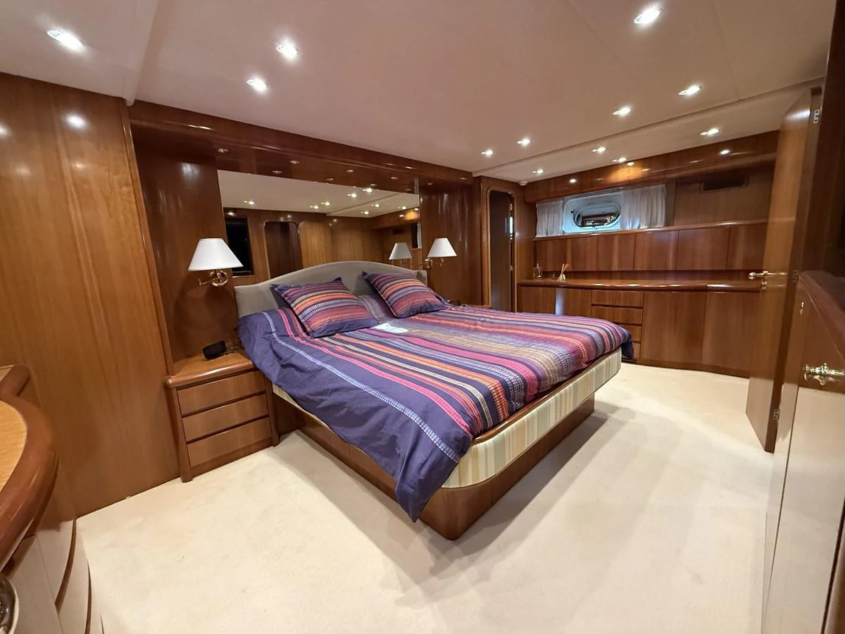 The master stateroom features a spacious bed with elegant wood paneling and ample lighting. aboard SIKOY Yacht for Sale