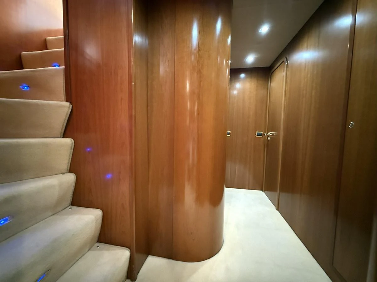A luxurious hallway with wooden paneling and carpeted stairs illuminated by soft lighting. aboard SIKOY Yacht for Sale
