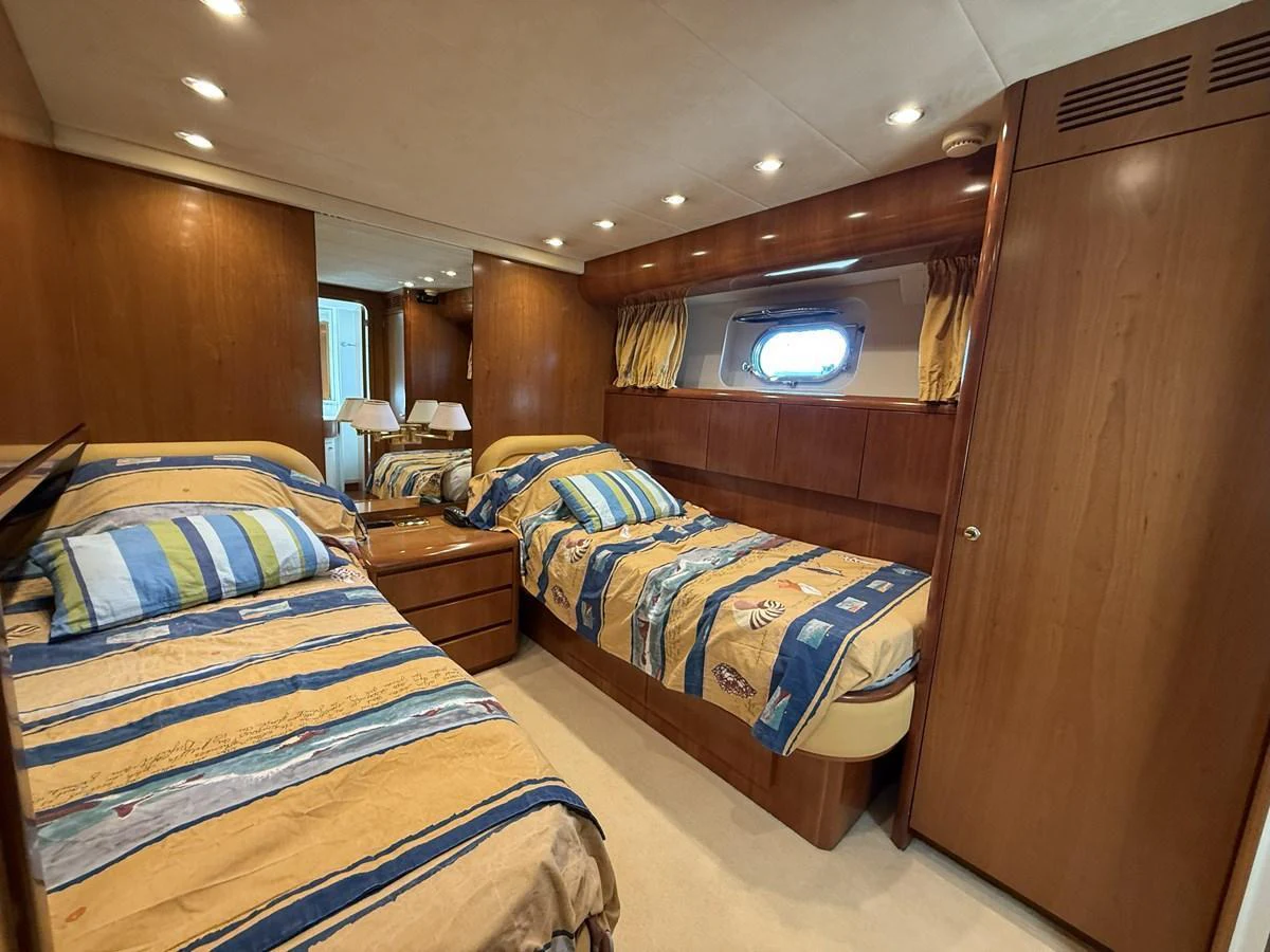 The twin stateroom features cozy twin beds with striped bedding and warm wood paneling. aboard SIKOY Yacht for Sale