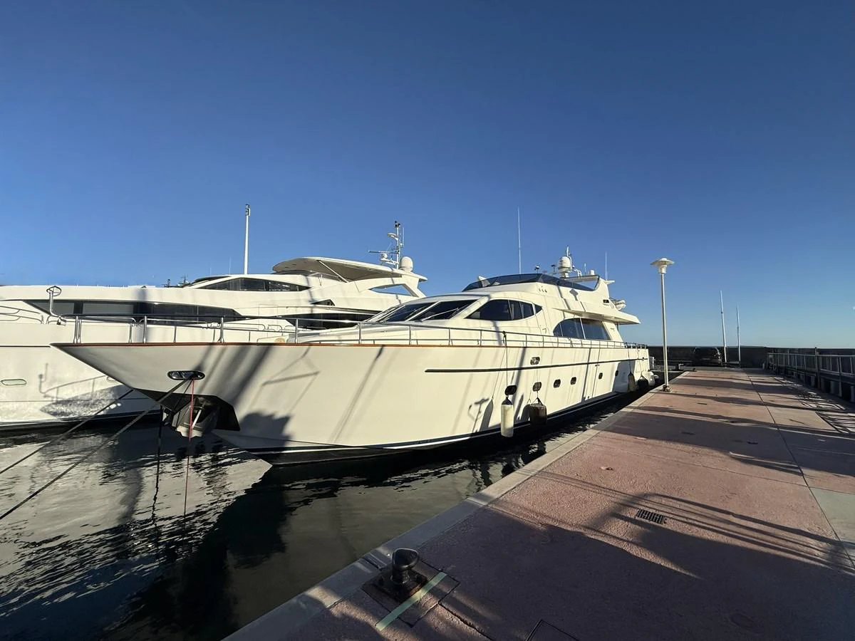 A sleek and elegant yacht docked at a marina under a clear blue sky. aboard SIKOY Yacht for Sale