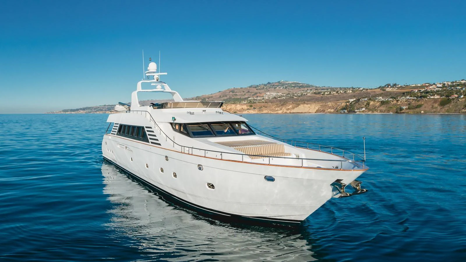 A sleek and elegant yacht cruising on calm waters with a scenic coastline in the background. aboard MONEY CAT Yacht for Sale