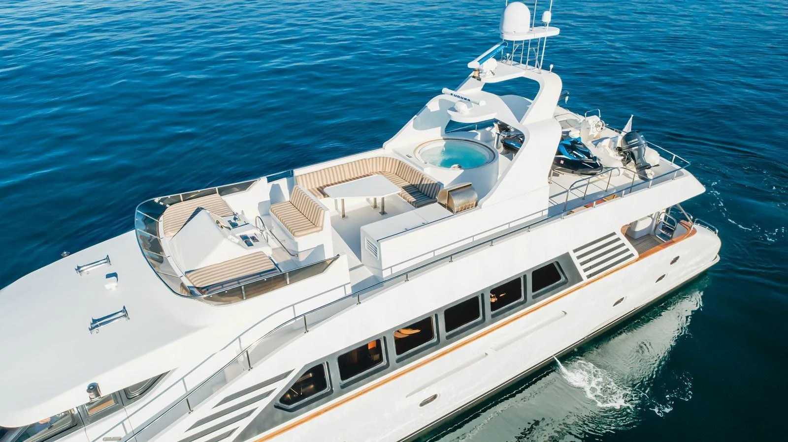 A luxurious yacht cruising on calm waters, showcasing its spacious flybridge with a jacuzzi and ample seating. aboard MONEY CAT Yacht for Sale