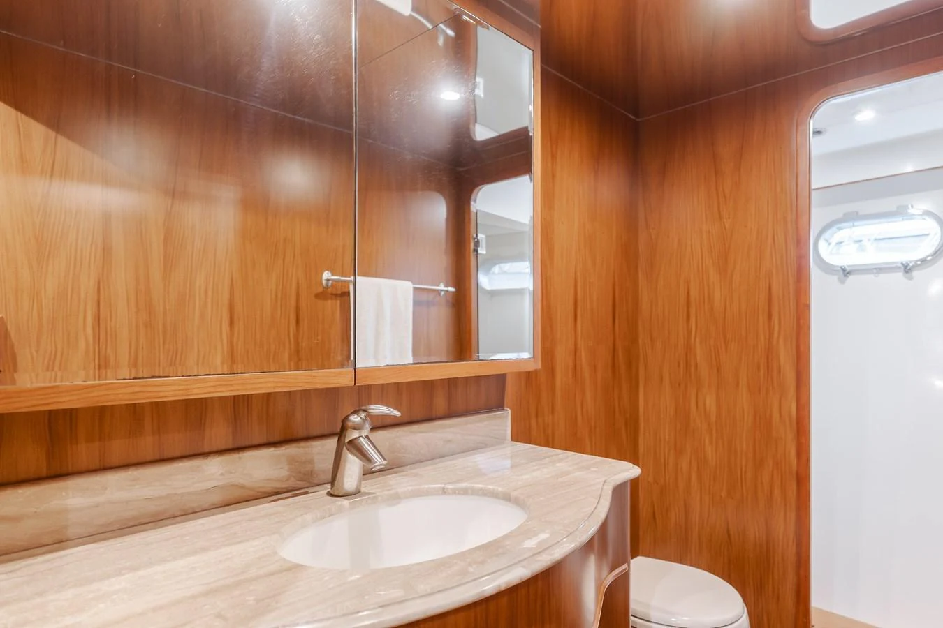 The yacht's bathroom features elegant wood paneling and a sleek marble countertop. aboard MONEY CAT Yacht for Sale