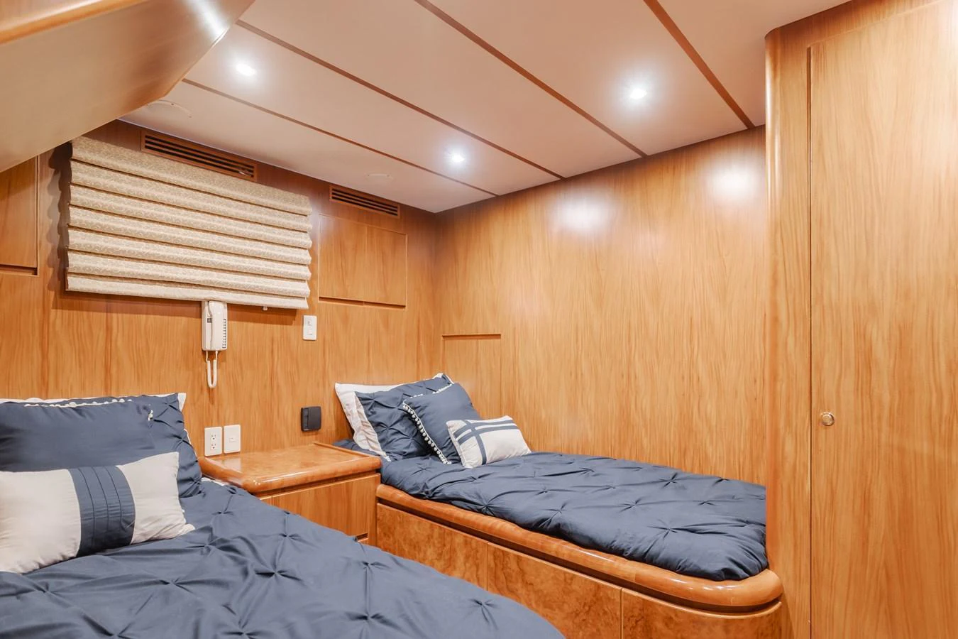 The twin stateroom features cozy twin beds with elegant wood paneling and modern lighting. aboard MONEY CAT Yacht for Sale