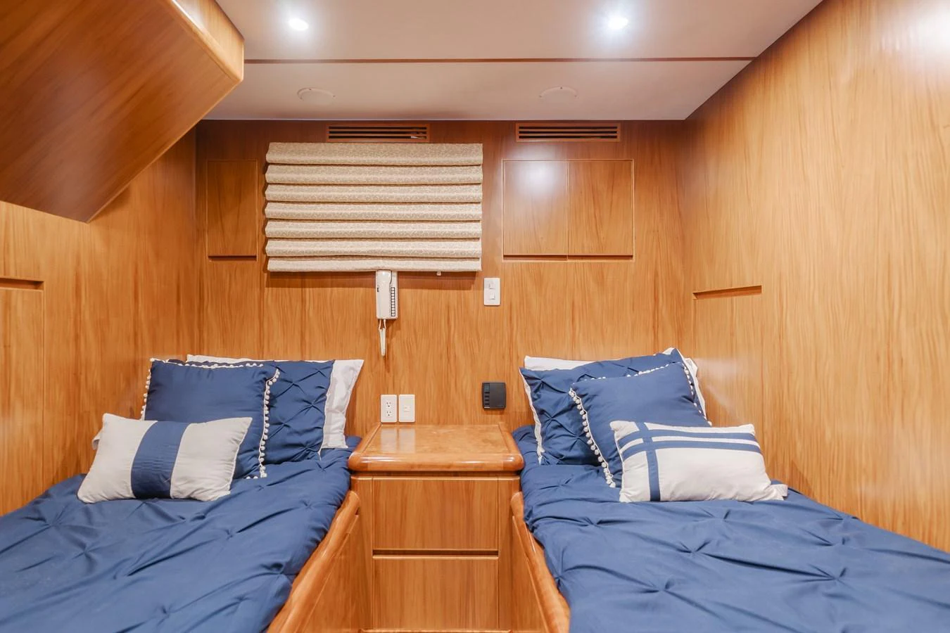 A cozy twin stateroom with wooden paneling and blue bedding. aboard MONEY CAT Yacht for Sale