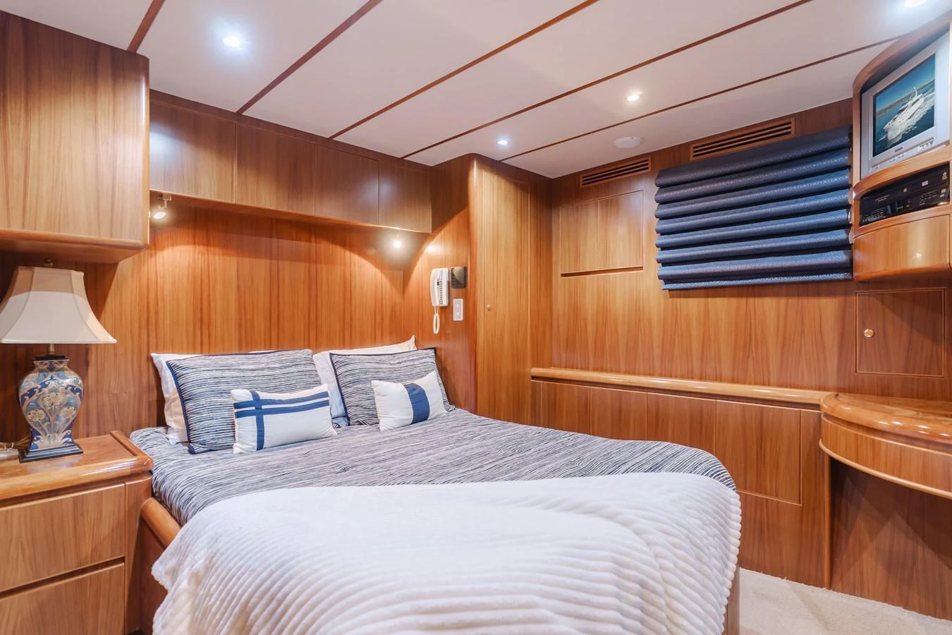 The cozy stateroom features a comfortable double bed with elegant wooden paneling and soft lighting. aboard MONEY CAT Yacht for Sale