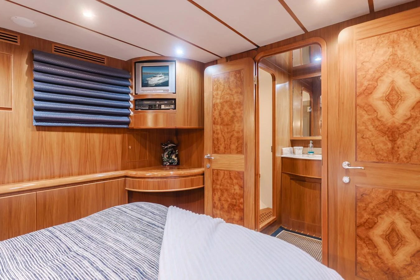 The stateroom features warm wood paneling, a cozy bed, and a private ensuite bathroom. aboard MONEY CAT Yacht for Sale