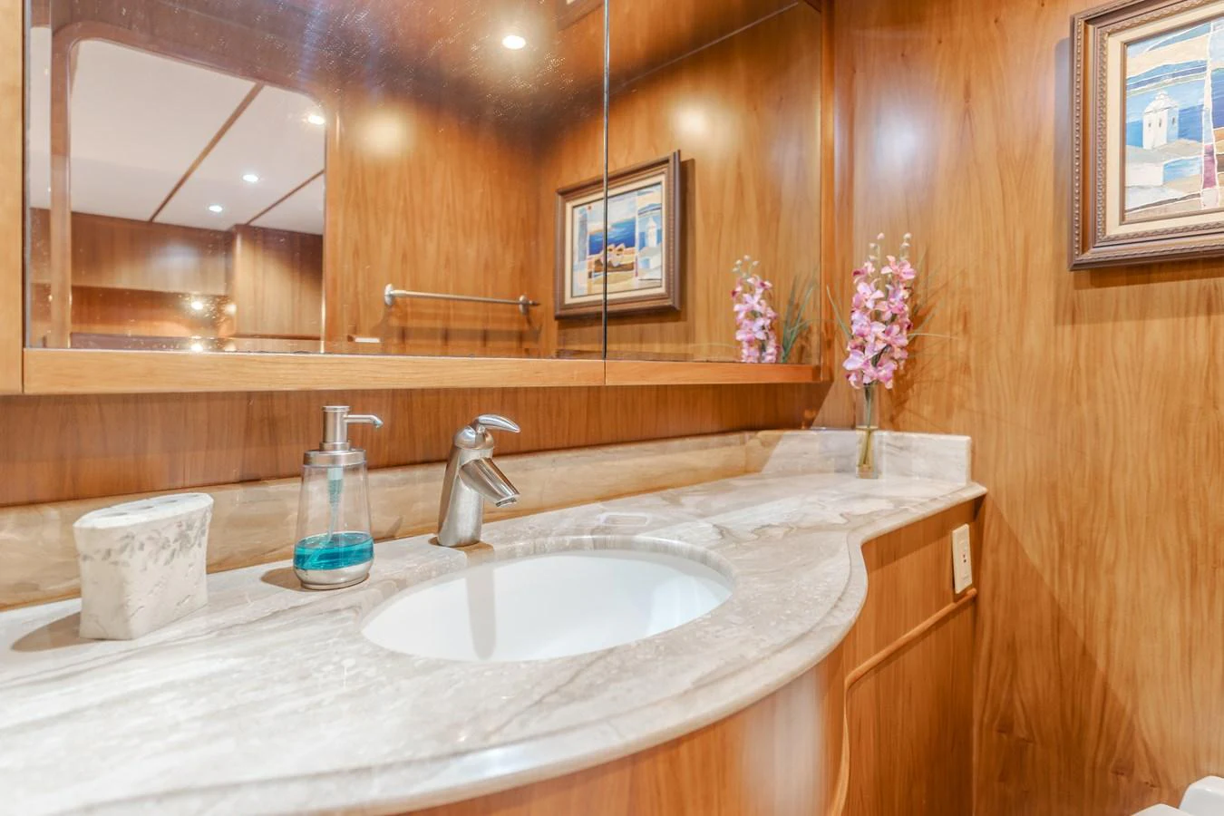 The yacht's bathroom features a sleek sink with elegant fixtures and warm wood paneling. aboard MONEY CAT Yacht for Sale
