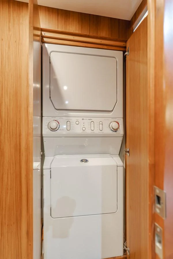 The yacht features a compact and efficient laundry area with a stacked washer and dryer. aboard MONEY CAT Yacht for Sale