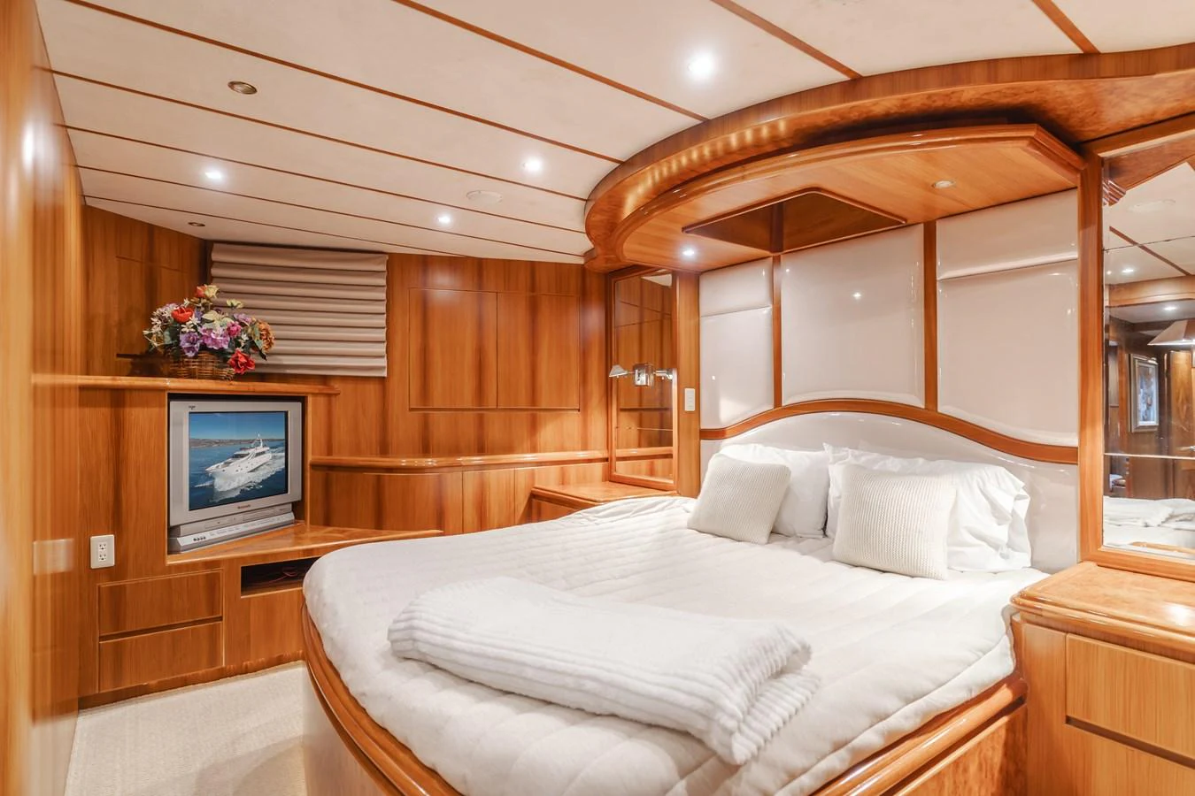 The stateroom features a luxurious bed with elegant wood paneling and a built-in entertainment system. aboard MONEY CAT Yacht for Sale