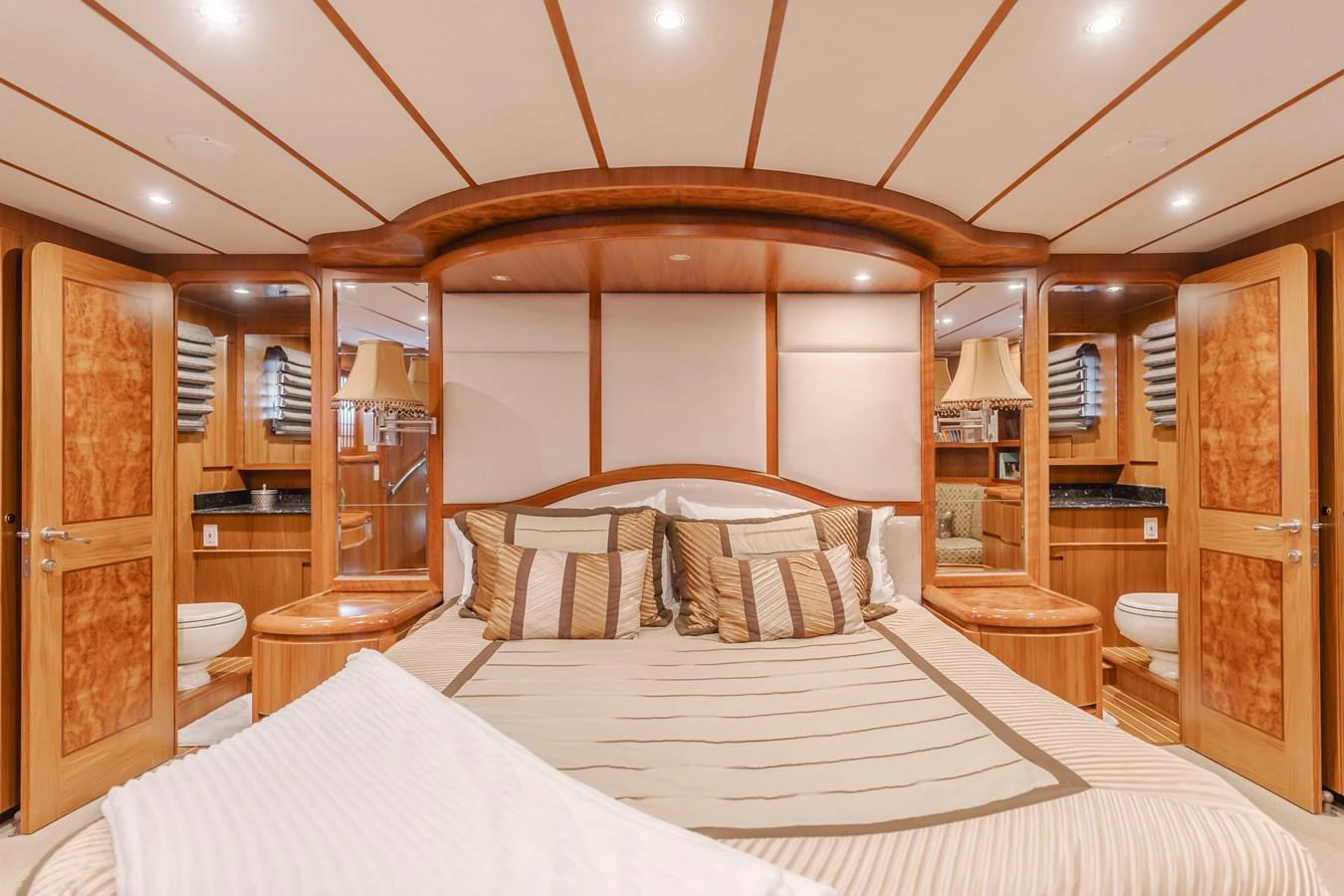 The master stateroom features a luxurious bed with elegant wood finishes and ample lighting. aboard MONEY CAT Yacht for Sale