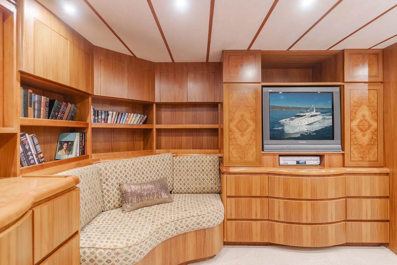 The yacht's cozy interior features a built-in sofa, wooden cabinetry, and a flat-screen TV. aboard MONEY CAT Yacht for Sale