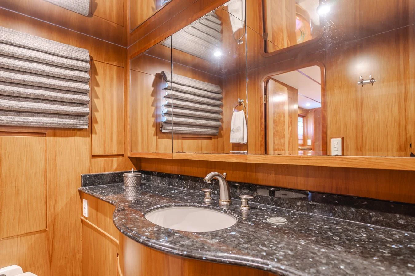 The yacht's bathroom features elegant wood paneling and a sleek granite countertop. aboard MONEY CAT Yacht for Sale