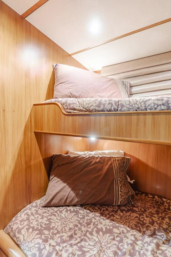 The cozy bunk cabin features warm wood paneling and comfortable bedding. aboard MONEY CAT Yacht for Sale