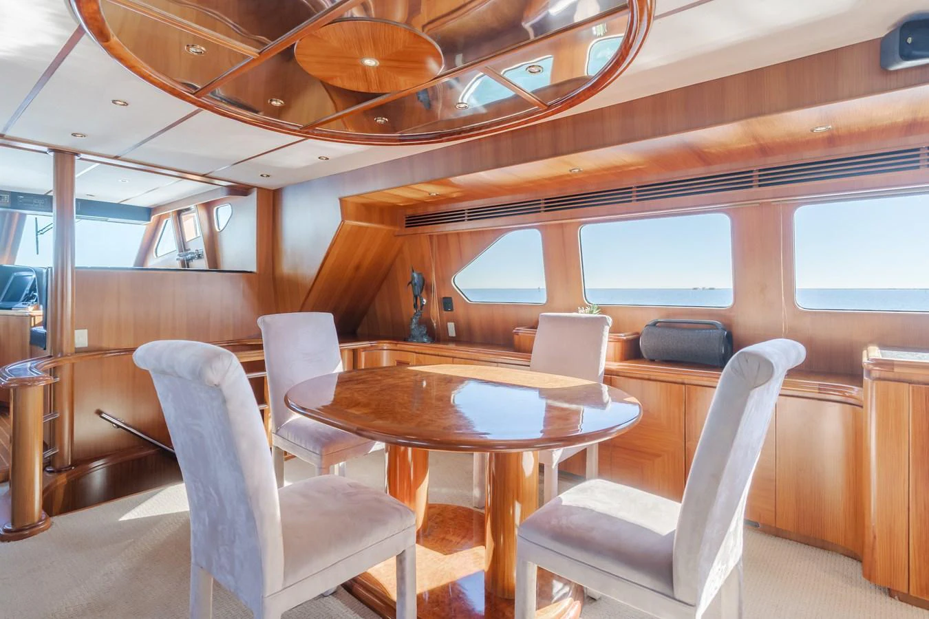 The yacht's dining area features a round wooden table surrounded by plush chairs, with large windows offering stunning sea views. aboard MONEY CAT Yacht for Sale