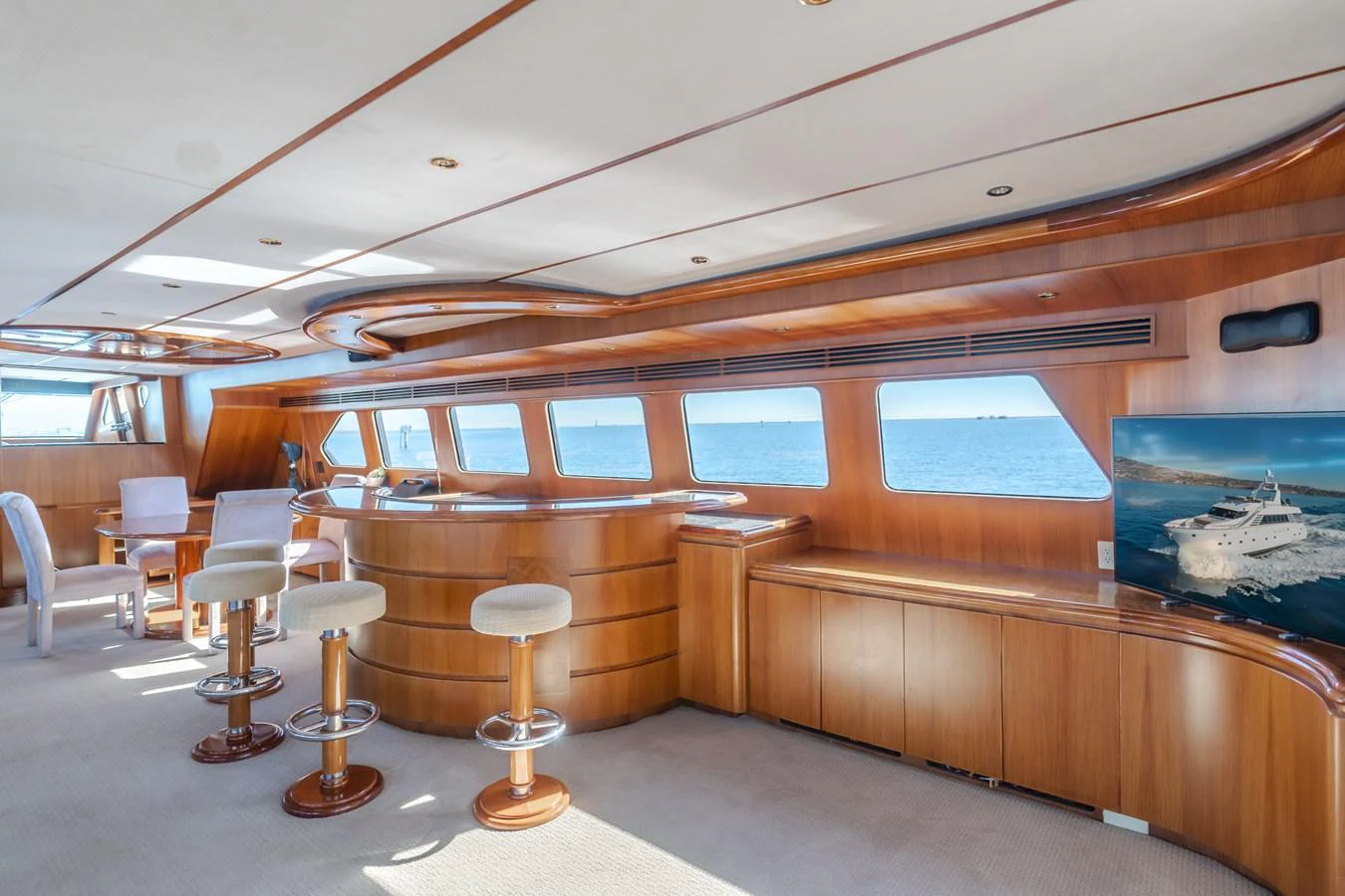 The salon features elegant wood paneling, a bar area, and large windows offering stunning sea views. aboard MONEY CAT Yacht for Sale