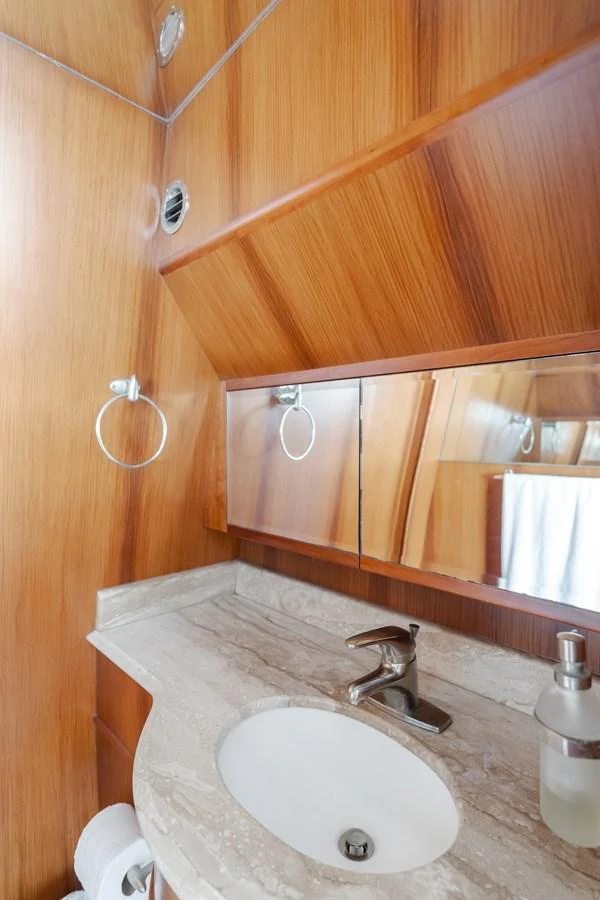 A sleek and modern yacht bathroom with wooden paneling and a marble countertop. aboard MONEY CAT Yacht for Sale