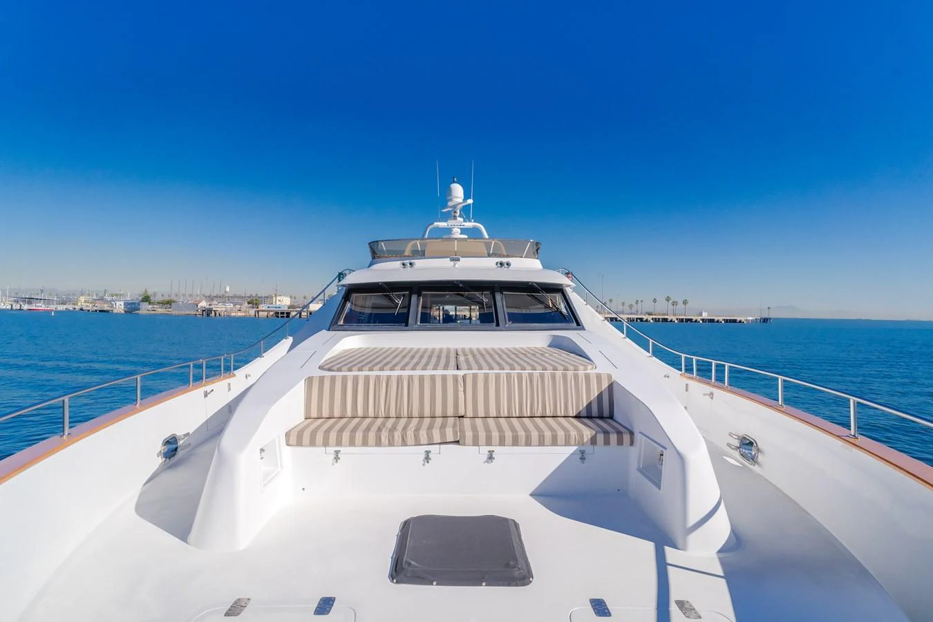 The yacht's foredeck offers a spacious sunbathing area with comfortable striped cushions under a clear blue sky. aboard MONEY CAT Yacht for Sale