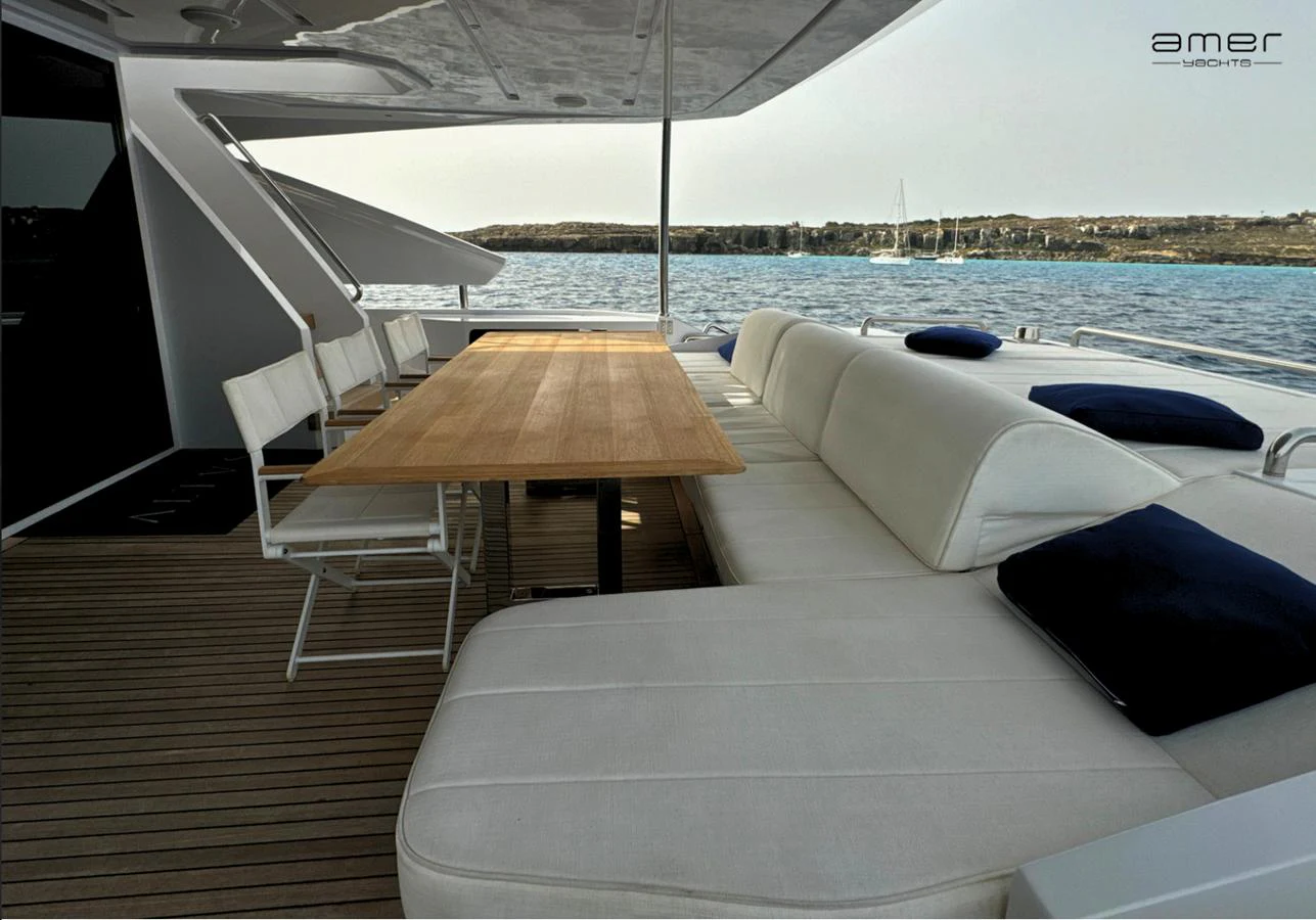 The aft deck features a spacious seating area with a wooden dining table, perfect for alfresco dining. aboard ALTUS Yacht for Sale