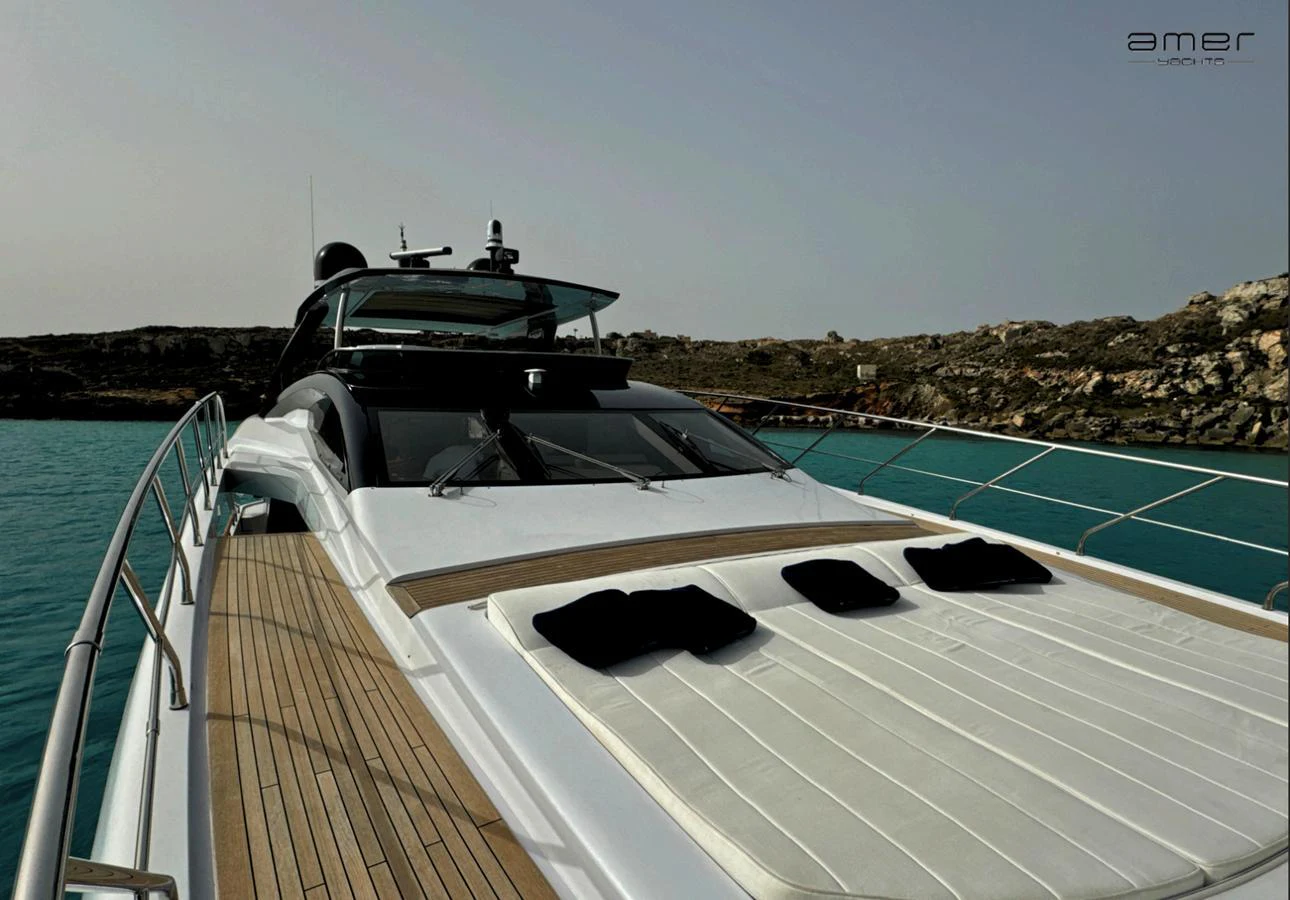 The yacht's foredeck features a spacious sunbathing area with plush cushions, set against a serene seascape. aboard ALTUS Yacht for Sale