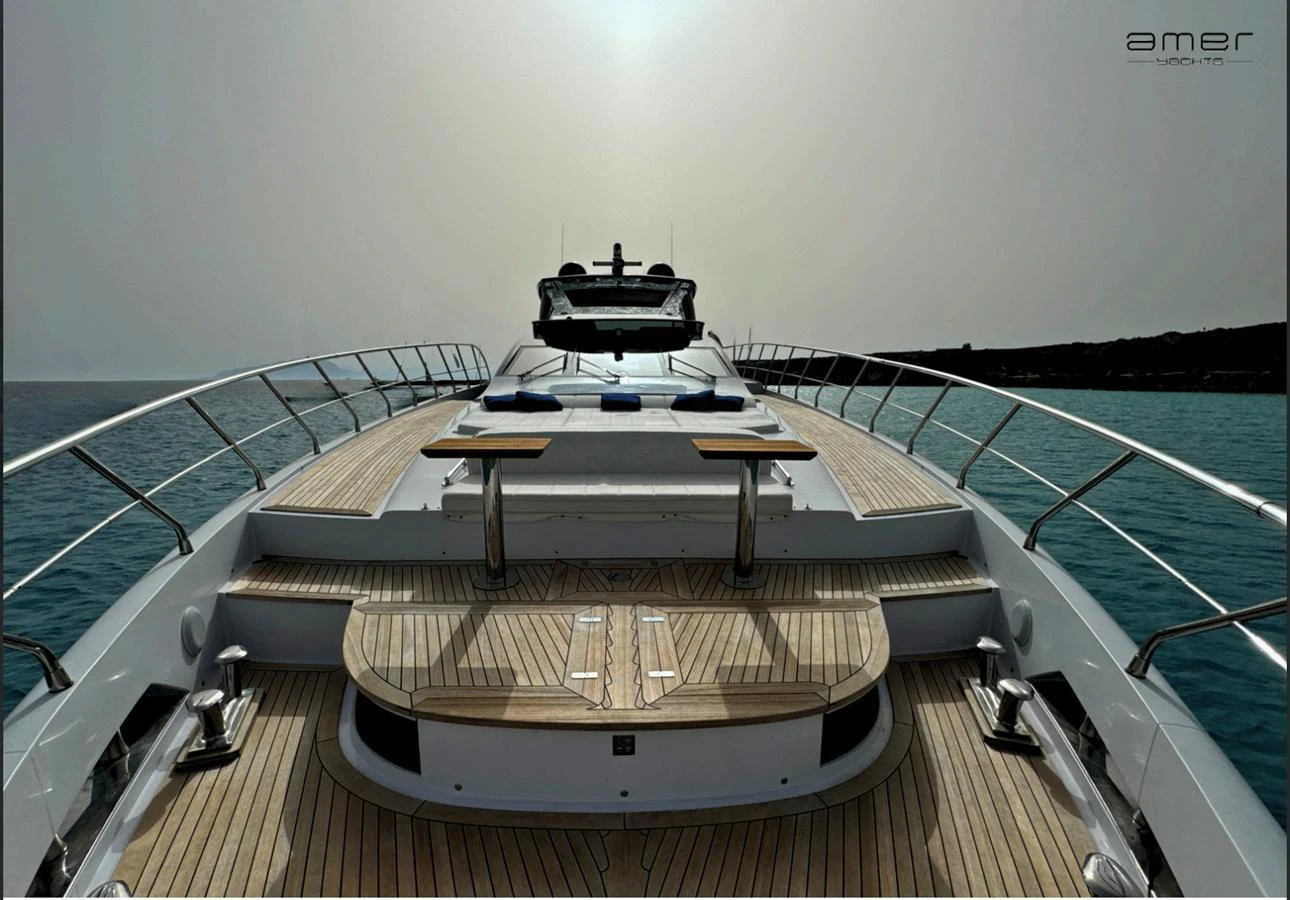 The yacht's foredeck features a spacious sunbathing area with luxurious sun pads and a dining table, set against a serene ocean backdrop. aboard ALTUS Yacht for Sale