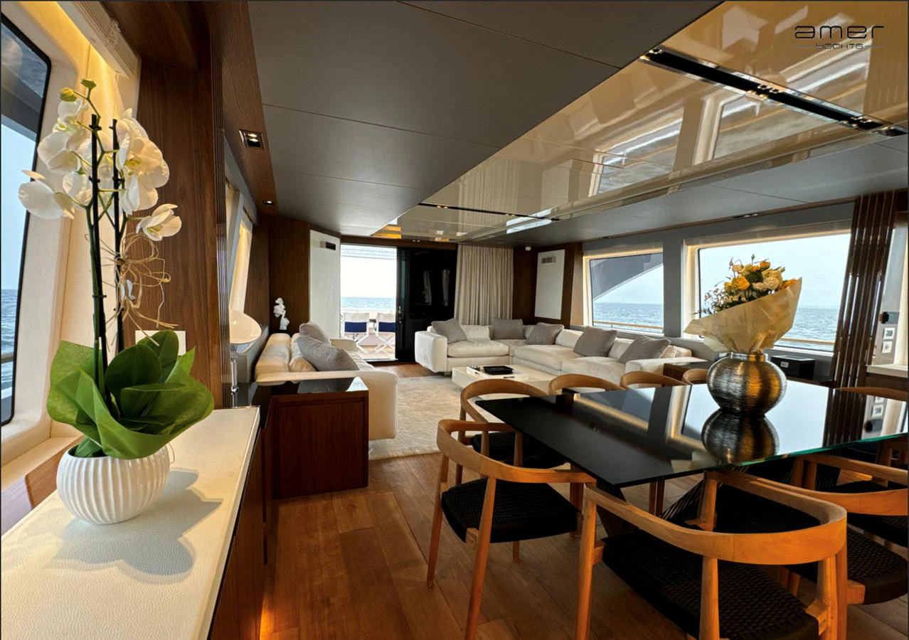 The salon features elegant furnishings with ample seating and panoramic windows offering stunning ocean views. aboard ALTUS Yacht for Sale