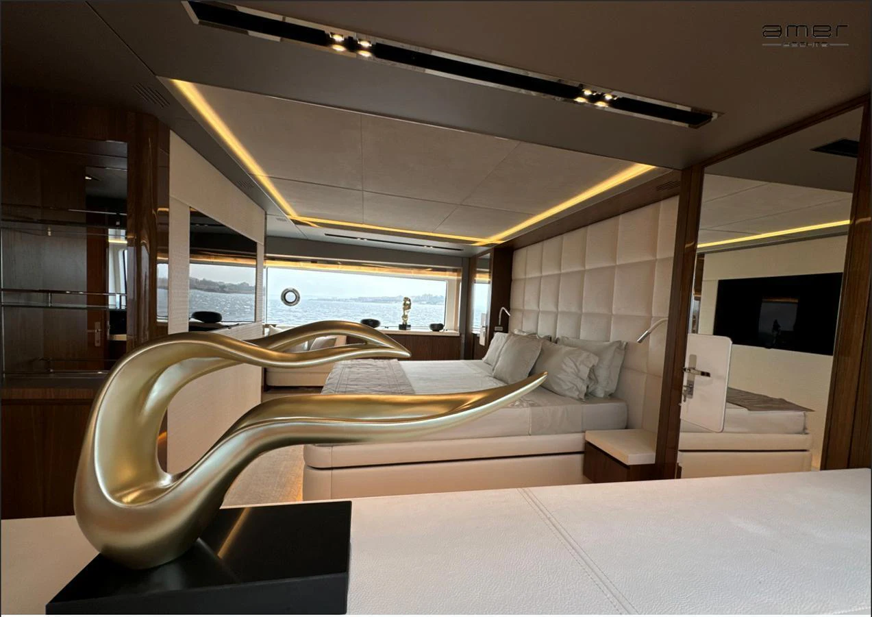 The master stateroom features a luxurious bed with a modern sculpture as a centerpiece, offering a serene view of the water through large windows. aboard ALTUS Yacht for Sale