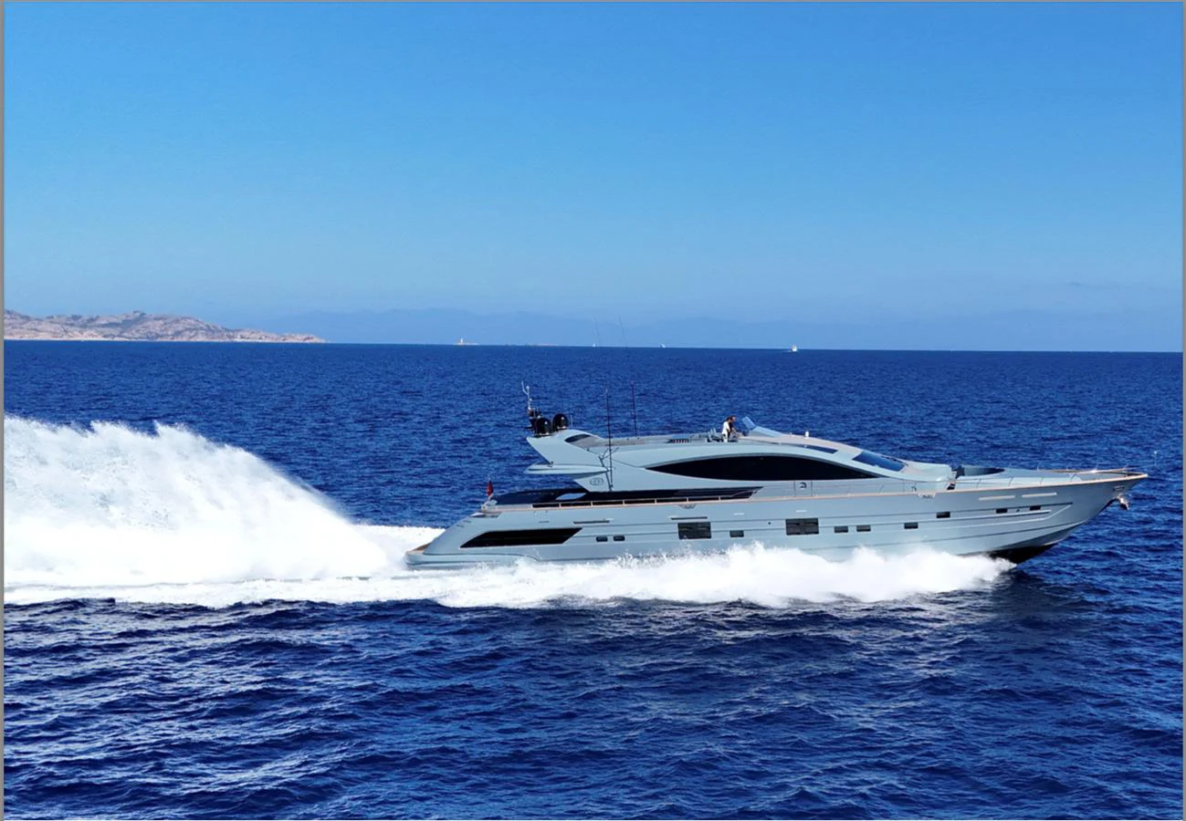 A sleek yacht cruises swiftly across the open sea under a clear blue sky. aboard DEEA II Yacht for Sale