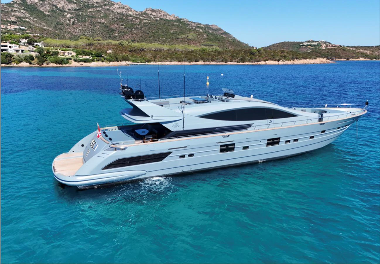 A sleek and modern yacht cruises through pristine turquoise waters with a scenic coastal backdrop. aboard DEEA II Yacht for Sale