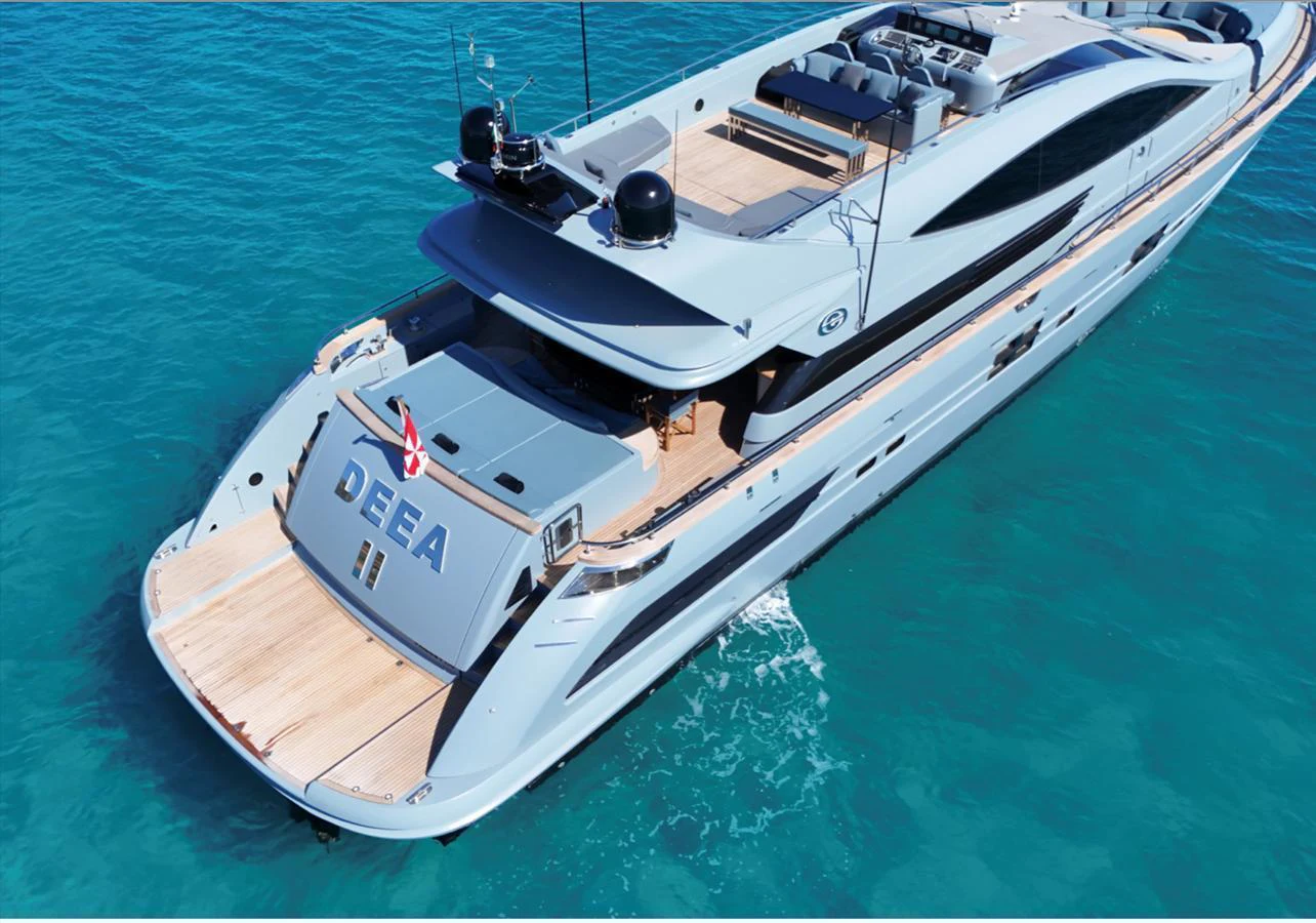A sleek and modern yacht glides effortlessly over clear blue waters, showcasing its elegant design and spacious deck areas. aboard DEEA II Yacht for Sale