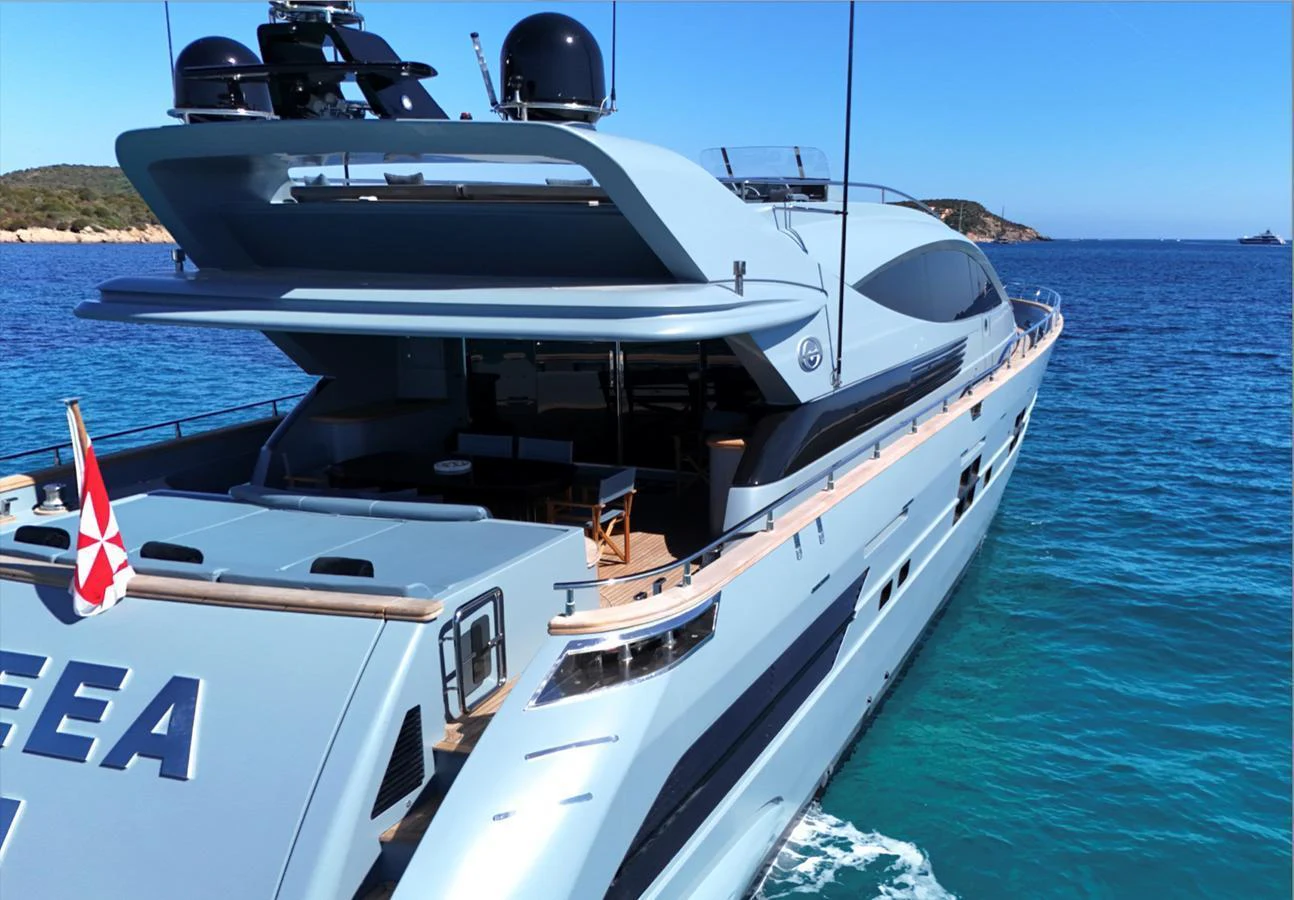 A sleek and modern yacht cruising in clear blue waters, showcasing its spacious aft deck and elegant design. aboard DEEA II Yacht for Sale
