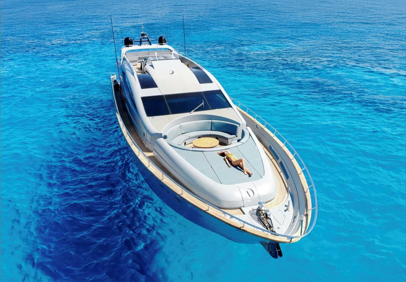 A sleek yacht cruises through crystal-clear blue waters, showcasing its modern design and luxurious sunbathing area on the bow. aboard DEEA II Yacht for Sale